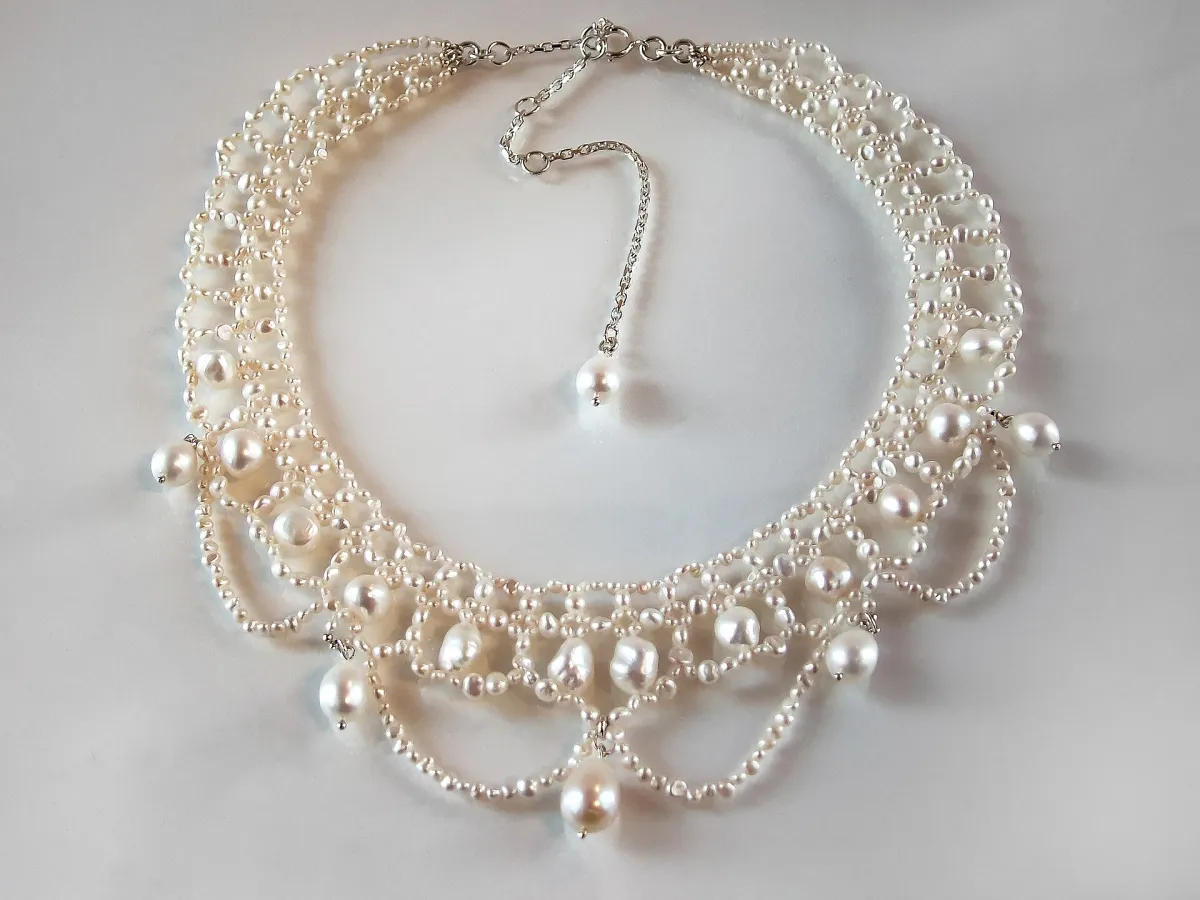 Collier de perles d'eau douce blanches posé sur un fond gris clair uni
